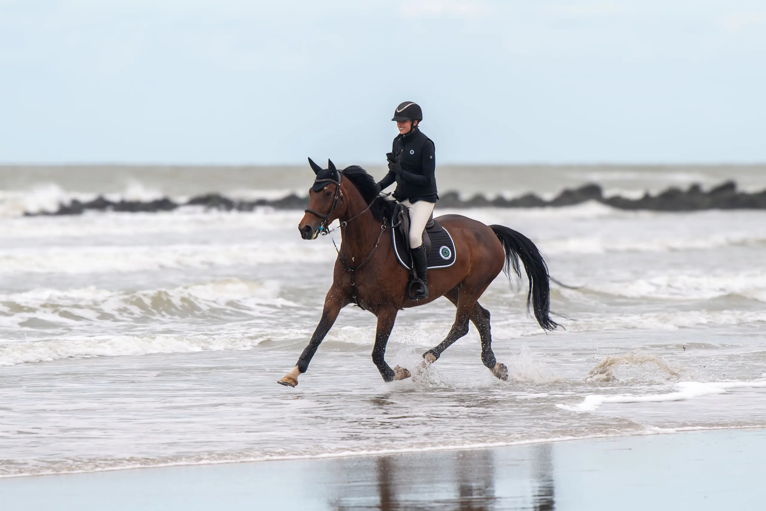 Ruiter galoppeert door de branding op het strand van Middelkerke